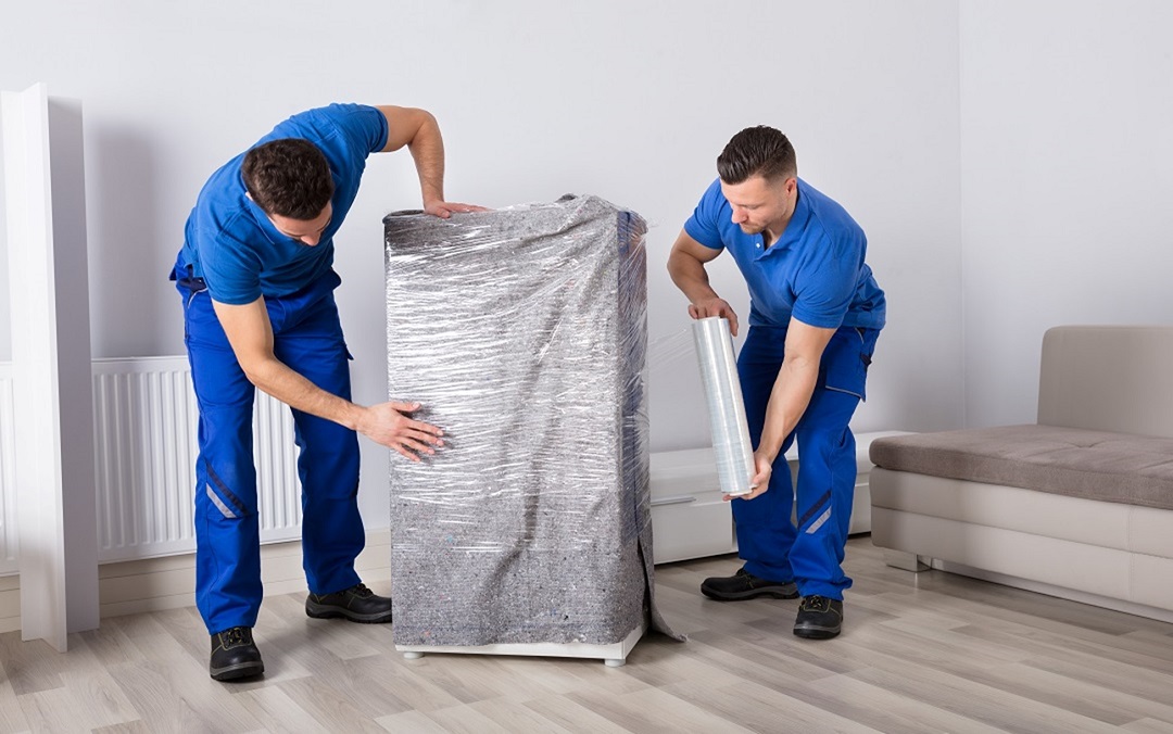 Two guys are wrapping a furniture